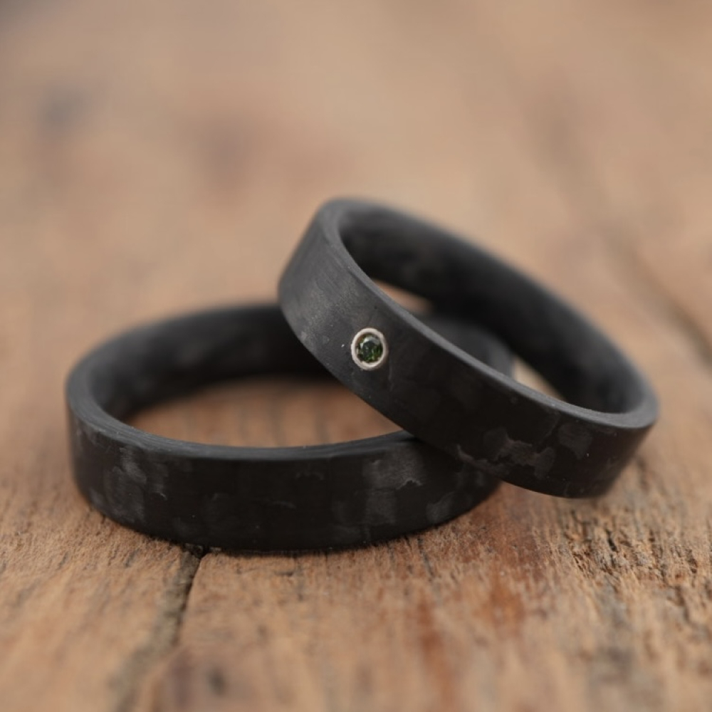Trauringe aus Carbon mit glatter Oberfläche und blauem Diamant