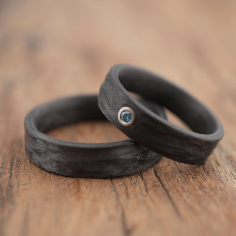 Trauringe aus Carbon mit Rinde-Oberfläche und blauem Diamant