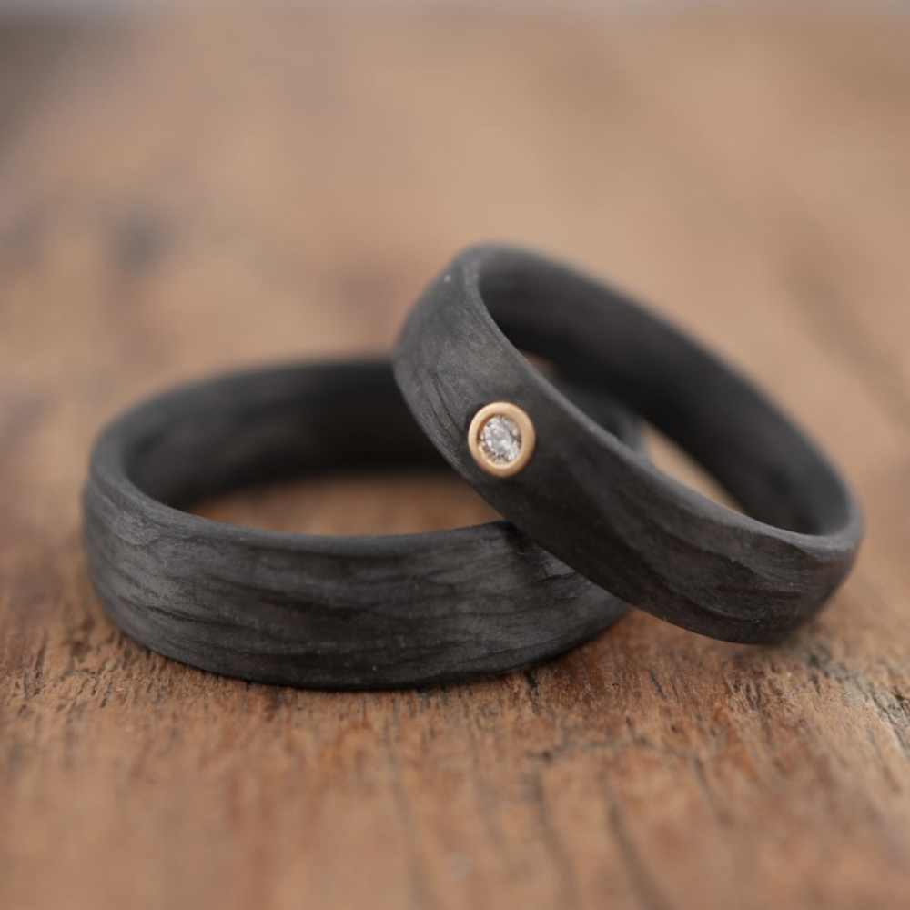 Trauringe aus Carbon mit Rinde-Oberfläche und Caramelgold-Fassung
