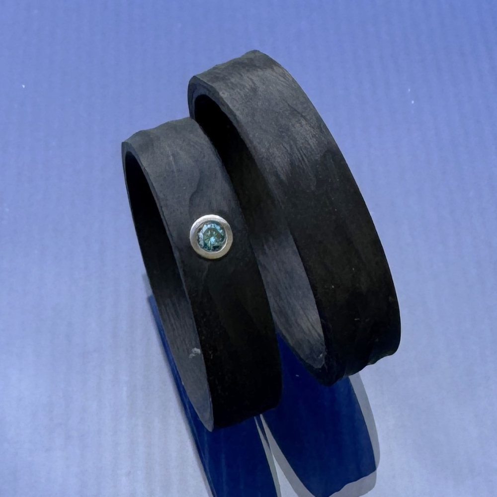 Preview: Trauringe aus Carbon mit Rinde-Oberfläche und blauem Diamant