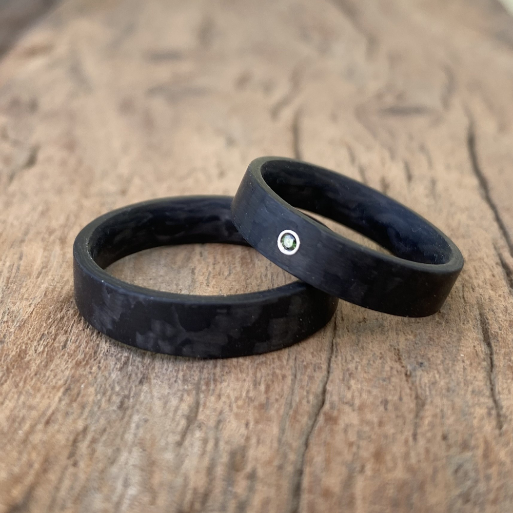 Trauringe aus Carbon mit glatter Oberfläche und blauem Diamant