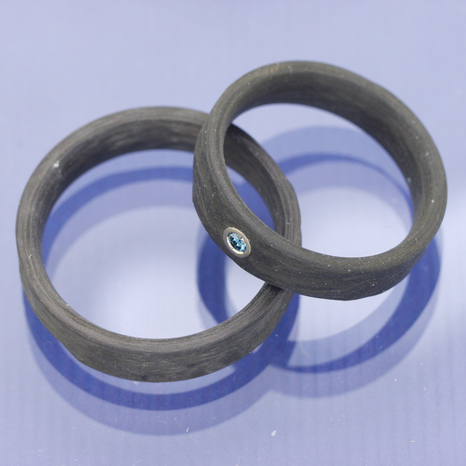 Trauringe aus Carbon mit Rinde-Oberfläche und blauem Diamant